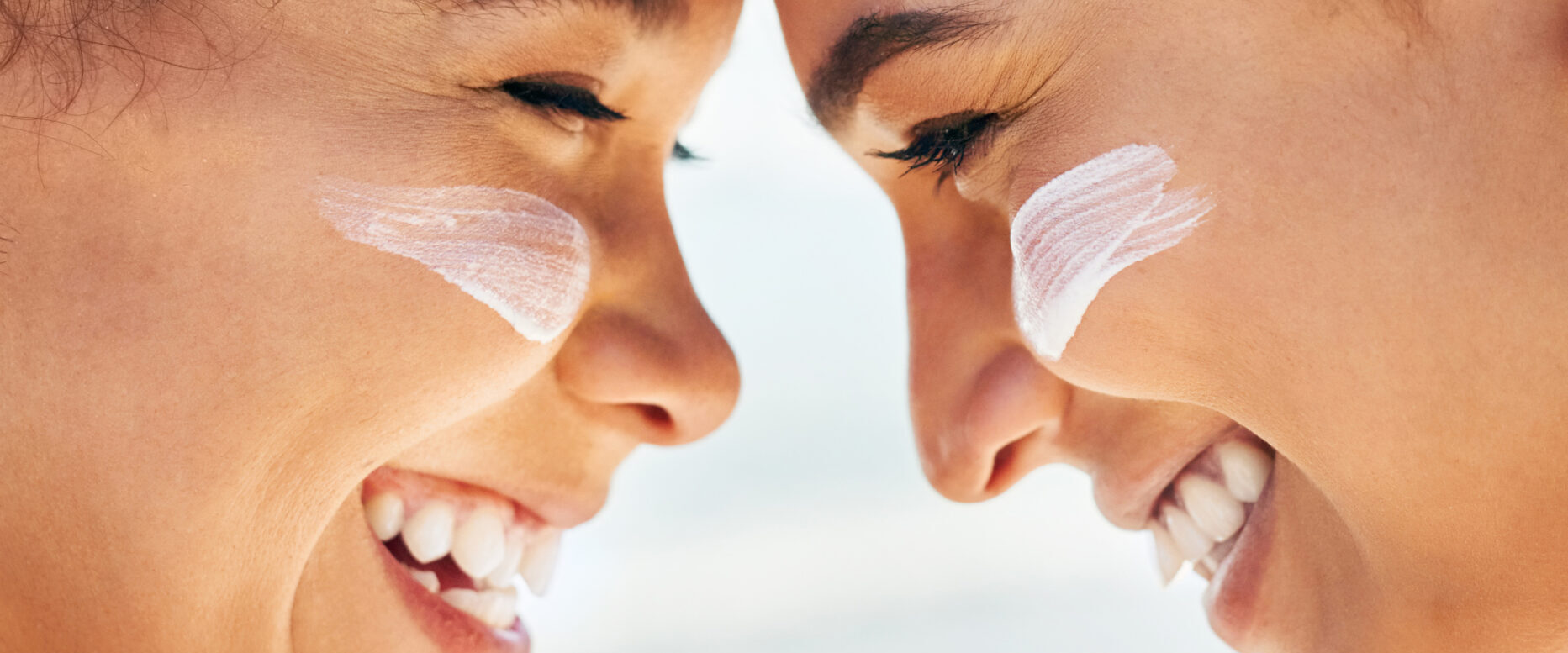 Sunscreen – Bring back the memories, not the burn. Shot of two b Shot of two beautiful young women at the beach with sunscreen on their faces smiling at each other.